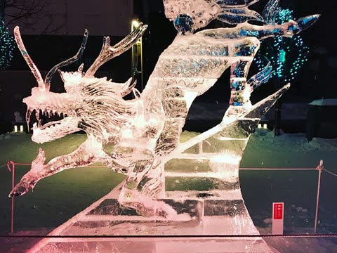 Ice sculpture of a dragon and fairy at night.