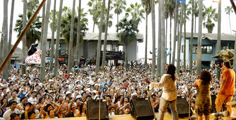 Band performing on stage for a large outdoor crowd.
