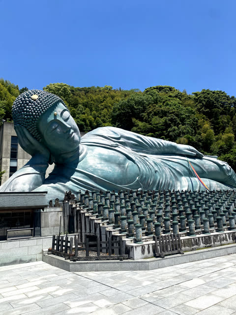 Large reclining Buddha statue outdoors, against a hillside.