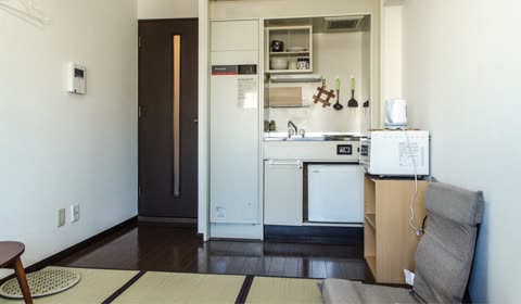 Small Japanese apartment kitchen with appliances and seating.