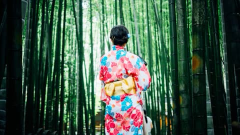 Woman in yukata walking through bamboo forest.