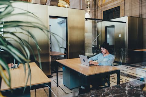 Man types on laptop at a desk in an office.