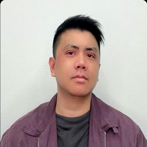 Man in purple jacket against a white wall.